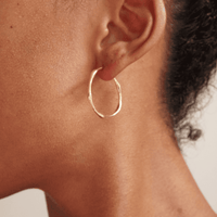 Gold hoop earring with a twisted, asymmetrical design, adding a modern touch to a classic style. This packshot highlights the unique shape and polished finish.