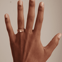 Gold ring in a signet ring design. Square signet ring on a brown hand