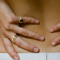 hand with nails on dots with golden rings on fingers, one golden signet ring and a stacked golden ring