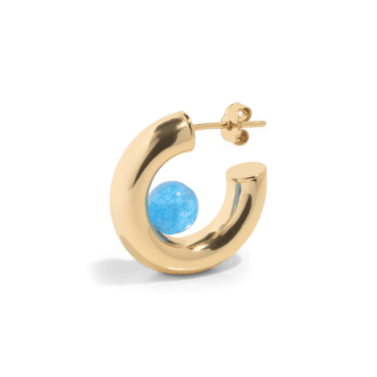 a gold hoop earring with a blue quartz gemstone positioned inside the open hoop