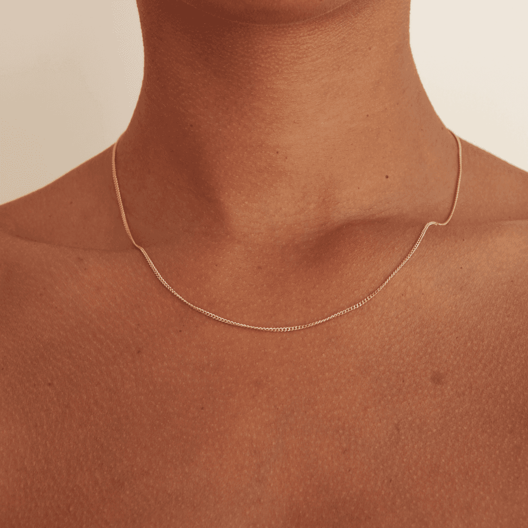 Delicate gold necklace chain on brown skin