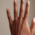 Close-up of a hand wearing a hammered gold ring with a textured finish, showcased against a neutral background. The minimalist design highlights timeless elegance and versatility.