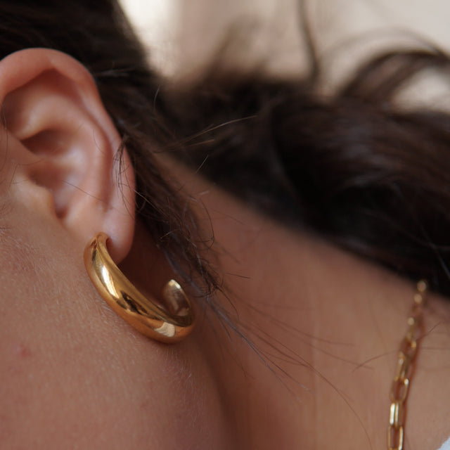 Woman's ear wearing gold hoop earring