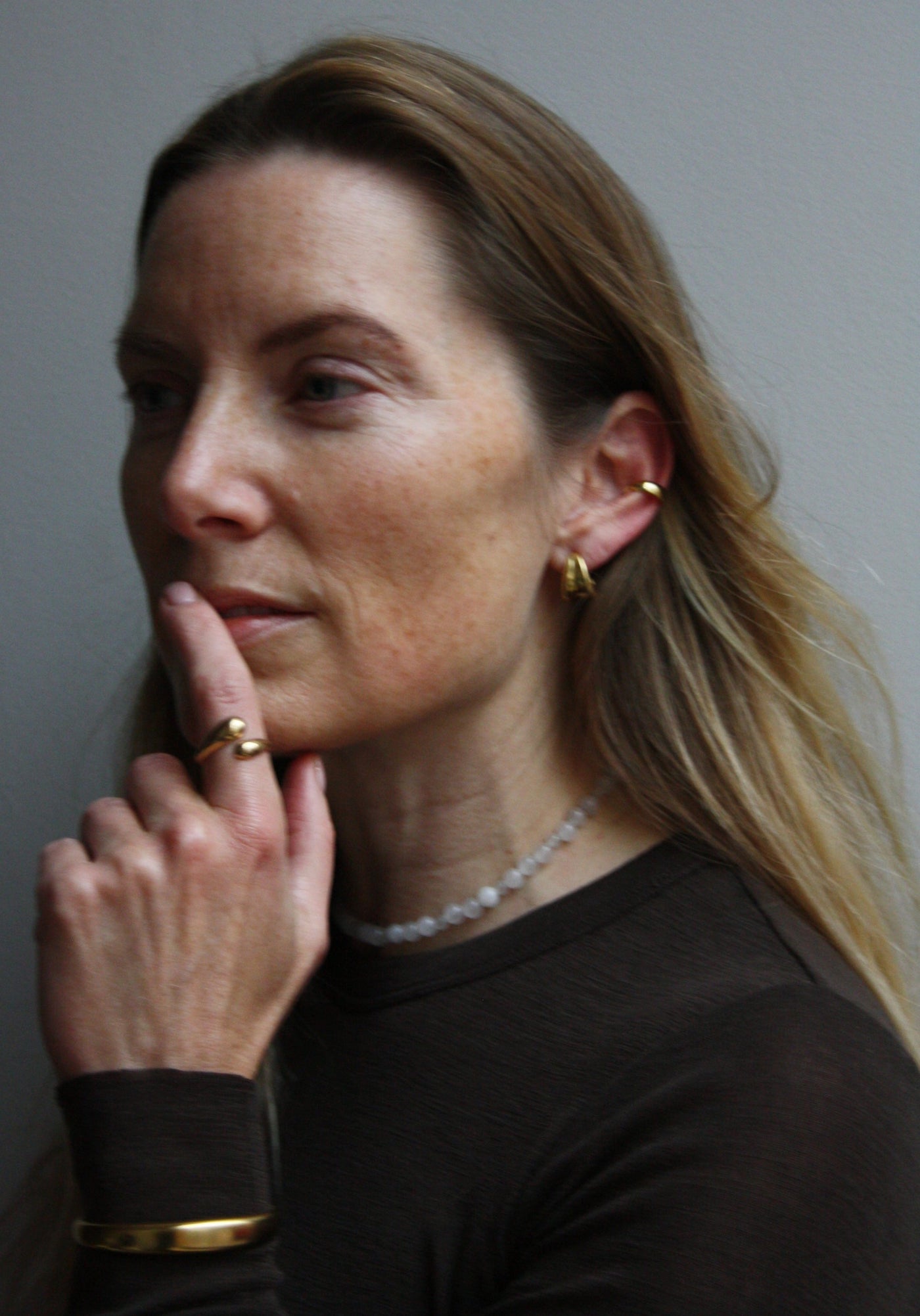 blonde woman with gold jewelry and a gemstone necklace