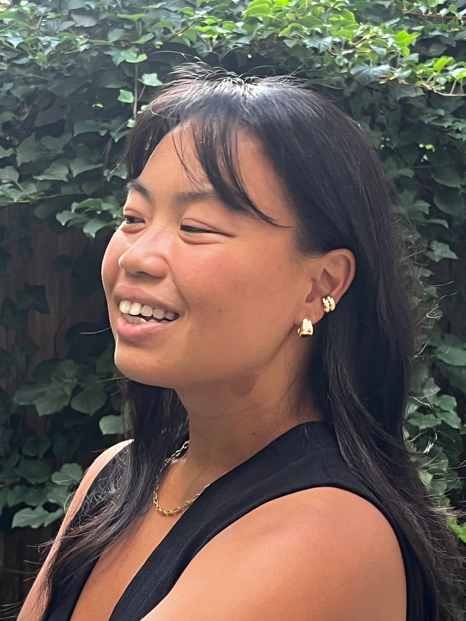 Close-up of a gold hoop earring, gold chain necklace and gold ear cuffs  on a model, highlighting its chunky and polished design. Perfect for adding a bold accent to any look.