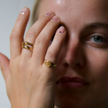 Blond girl with hand in front of face with a golden ring set and signet ring