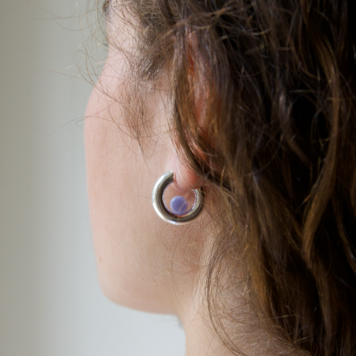 Woman wearing a silver bold hoop with a blue lace agate gemstone positioned inside