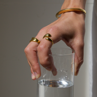 Close-up of a woman's hand wearing a unique gold ring with a wrap-around design, adding a bold yet elegant accent.