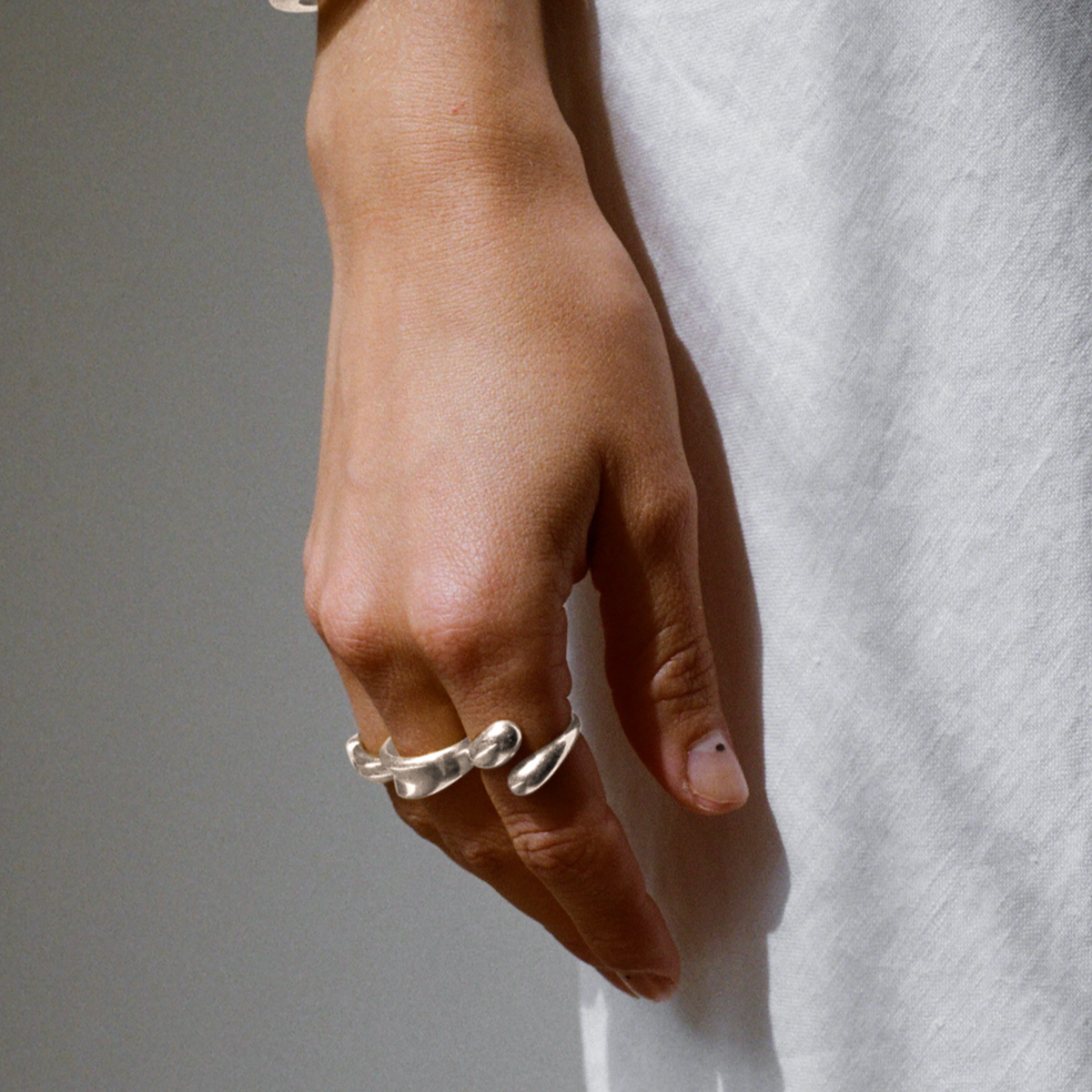 Close-up of a woman's hand wearing a unique silver ring with a wrap-around design, adding a bold yet elegant accent