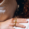 Close-up of a woman's hand wearing a unique gold ring with a wrap-around design, adding a bold yet elegant accent.