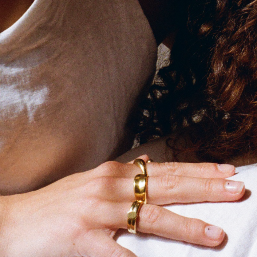 Close-up of a woman's hand wearing a unique gold ring with a wrap-around design, adding a bold yet elegant accent.