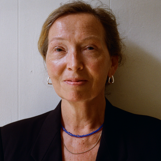 Lady in a black blazer wearing a silver triangle twisted earring, a silver rolo chain necklace and a blue quartz gemstone necklace.