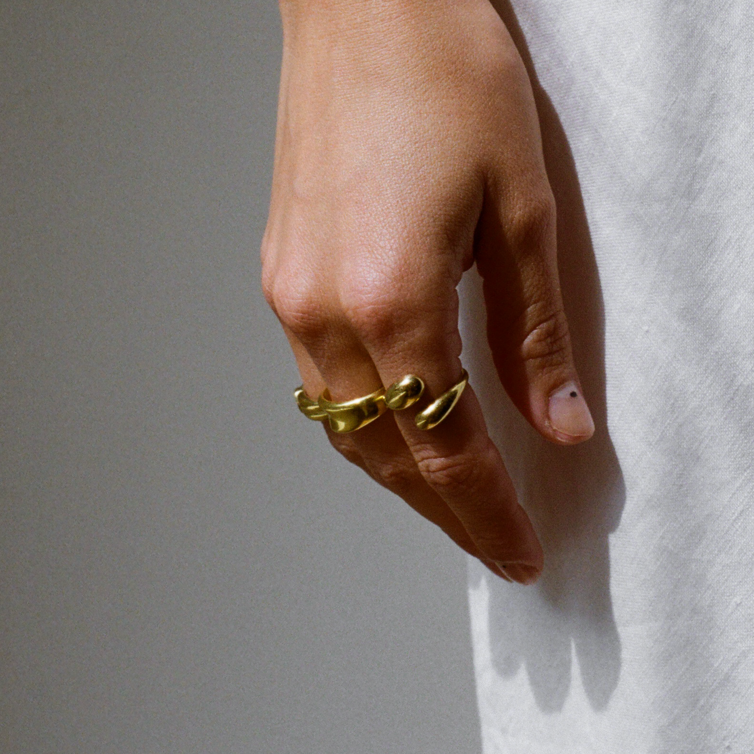 Close-up of a woman's hand wearing a unique gold ring with a wrap-around design, adding a bold yet elegant accent.