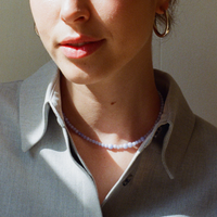 Woman in a grey shirt, with a blue lace agate gemstone necklace and a bold large hoop earring