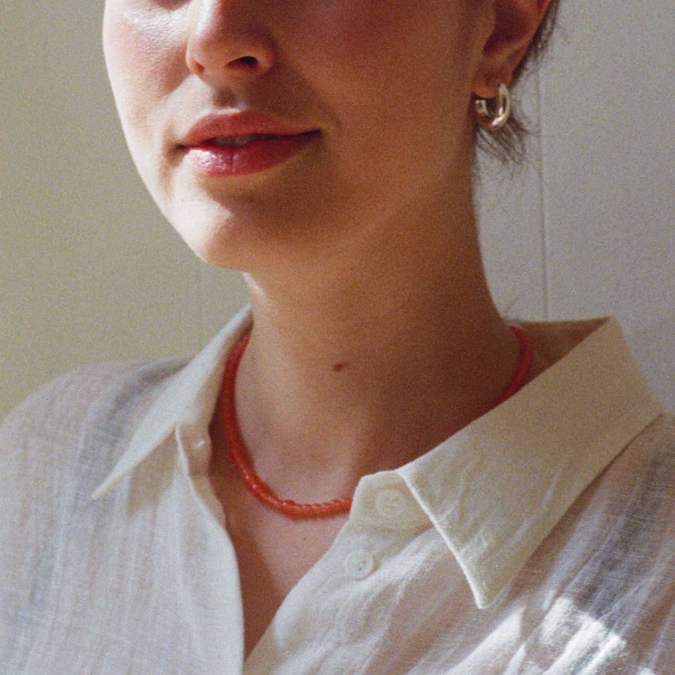 Woman in a white shirt wearing a tangerine quartz gemstone necklace and a silver bold hoop