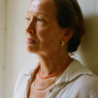 Lady in a white shirt wearing an orange tangerine gemstone necklace, a gold rolo necklace and a gold bold hoop with a tangerine quartz gemstone inside