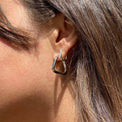 Sterling silver hoops with triangle twisted design on a woman with brown hair