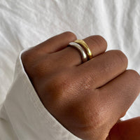 a close up of a person with Set of two rings in gold and silver with smooth, irregular bands, offering a modern twist on classic styles. These stack of rings showcases the minimalist and versatile design, perfect for stacking or wearing individually.