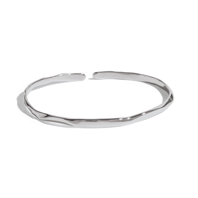 silve cuff bracelet with a slim, uneven design, offering a minimalist and modern look. This jewelry packshot showcases the bracelet's unique texture and open-ended style