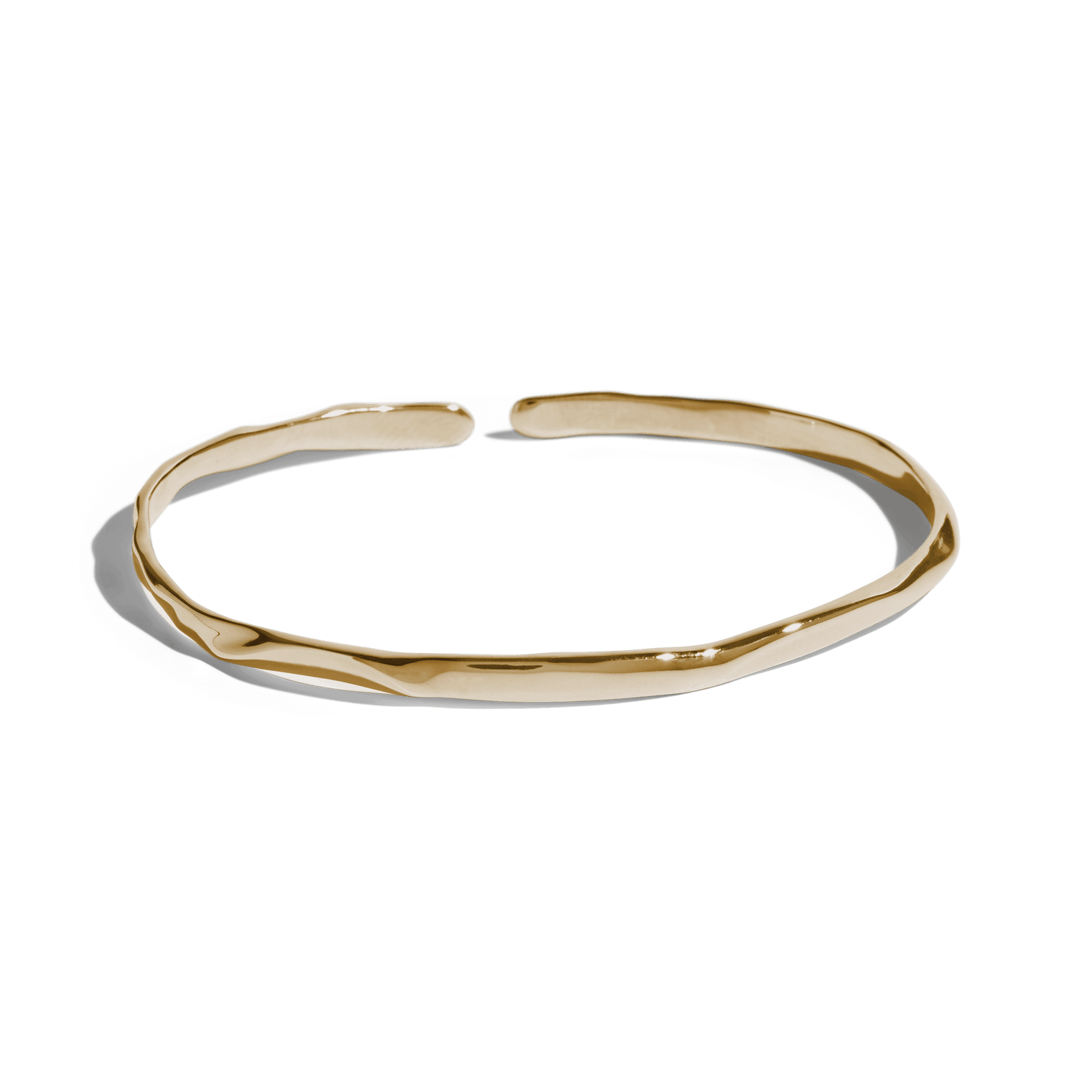 Gold cuff bracelet with a slim, uneven design, offering a minimalist and modern look. This jewelry packshot showcases the bracelet's unique texture and open-ended style